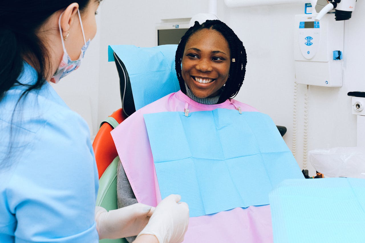 services-03 A smiling woman receives dental check-up from a practitioner in modern clinic.